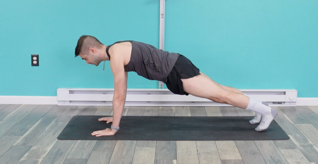 Dr. Jon in a plank position with his hands underneath his shoulders and weight on his toes. he is a straight line from the back of his neck to his heels